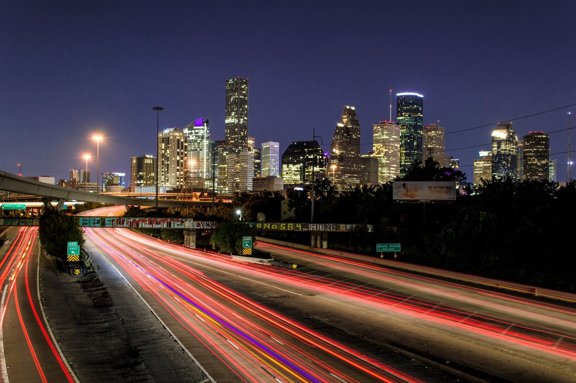 Houston skyline at night with freeway light trails.